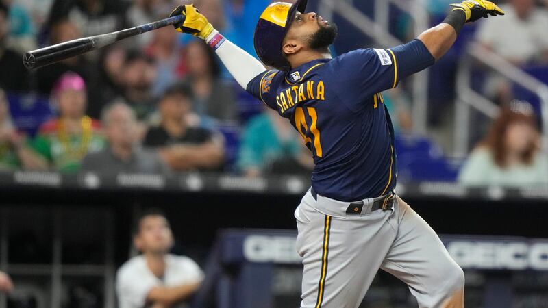 Milwaukee Brewers' Carlos Santana follows through on a single during the eighth inning of a...