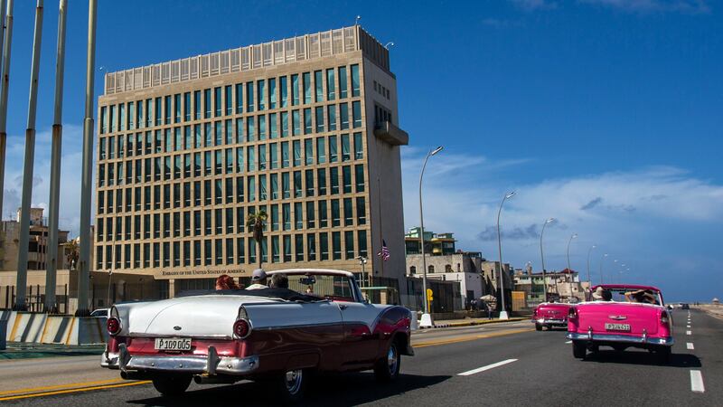 FILE - Tourists ride classic convertible cars beside the U.S. Embassy in Havana, Cuba, on Oct....